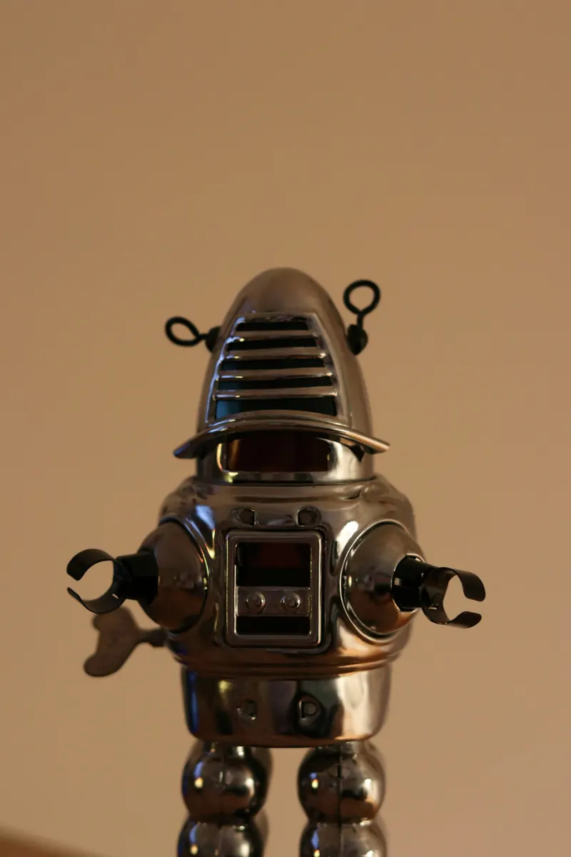 Silberner Aufziehroboter aus Blech vor braunem Grund