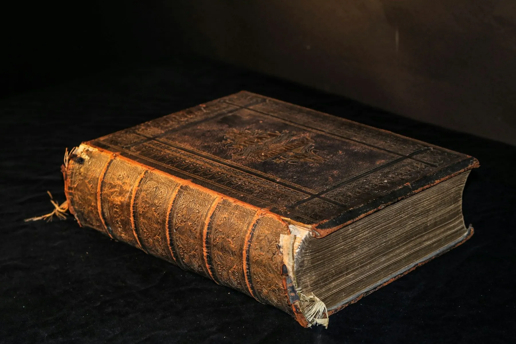 Thick leather book with a worn spine on black velvet