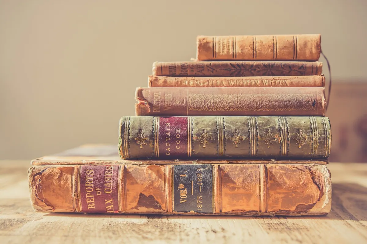 Stack of leather-bound books on light wood