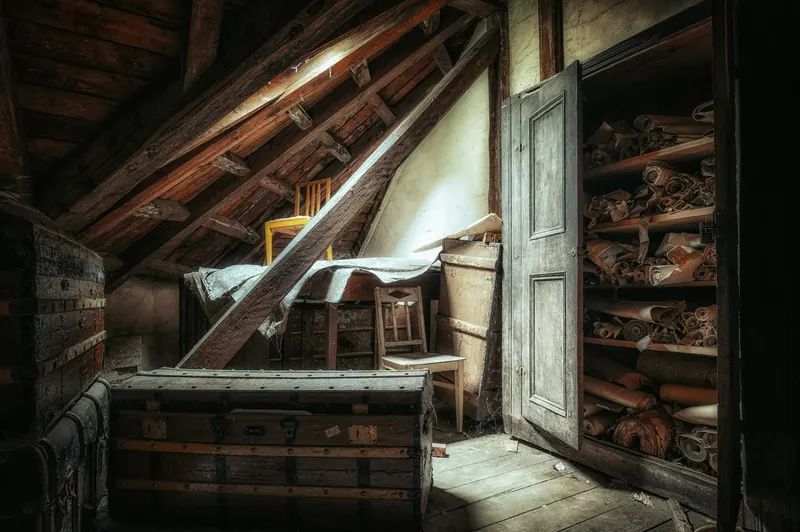 Attic with a chest, a chair and an open cupboard in raking light