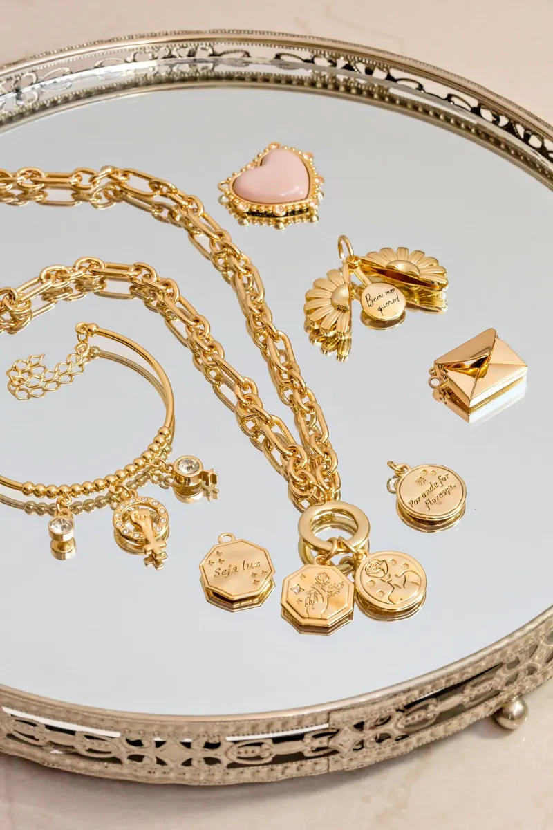 Chaînes en or, pendentifs et médaillons sur un plateau miroir