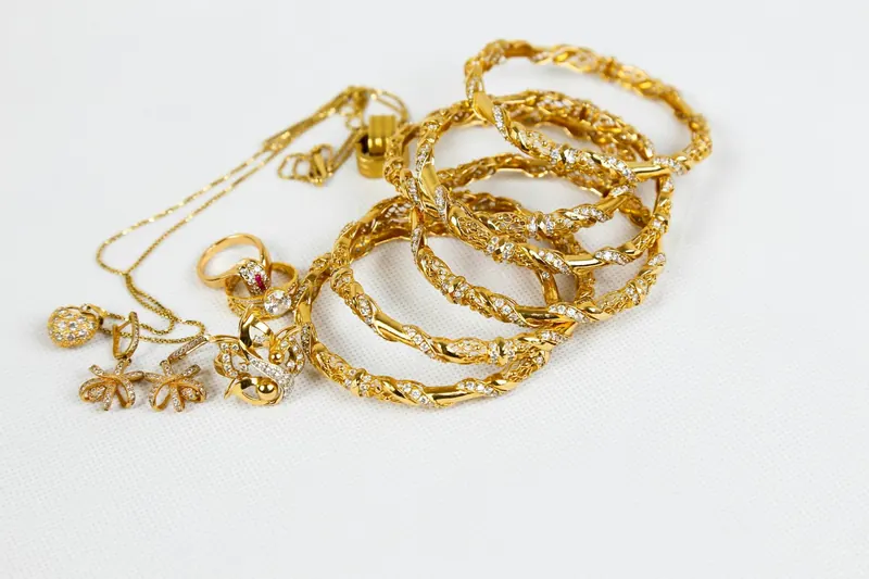 Gold bangles, chains and rings on a white background