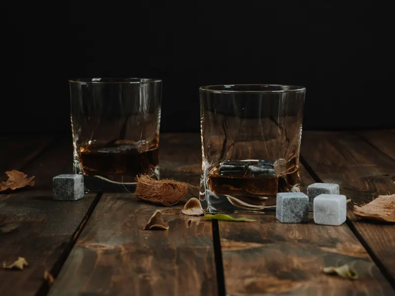 Two whisky glasses with whisky stones on a dark wooden table
