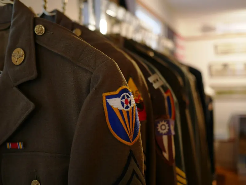 Olive green uniform jackets on a clothes rail